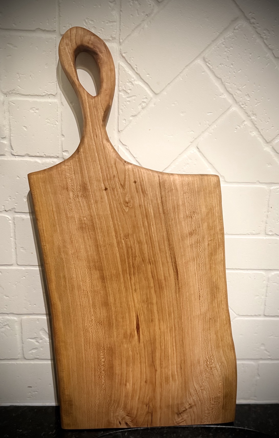 Cherry charcuterie board with flowing grain and sculpted handle
