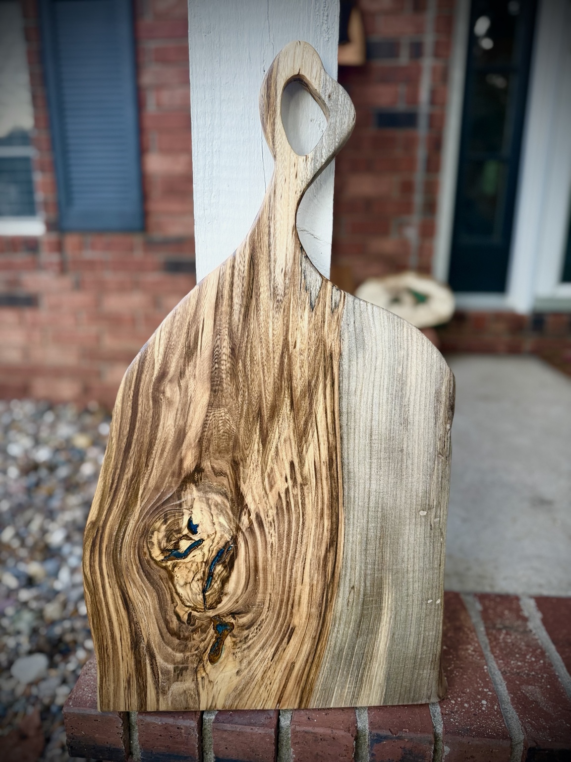 Handcrafted Hackberry charcuterie board with sculpted handle and small blue resin accents