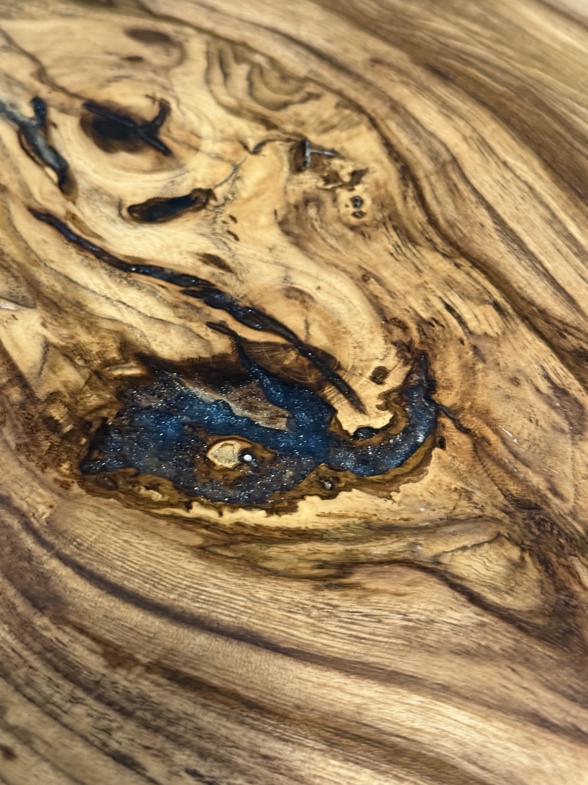 Close-up of the Hackberry charcuterie board showing dramatic natural grain and blue resin detail